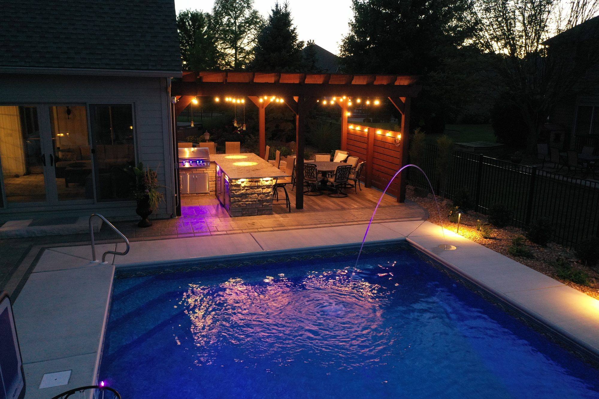 Overhead view of a pool and pergola with string lights over the dining area