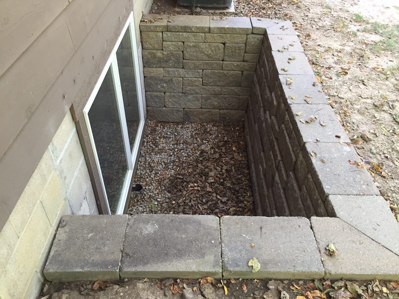 Block retaining wall built around a basement egress window