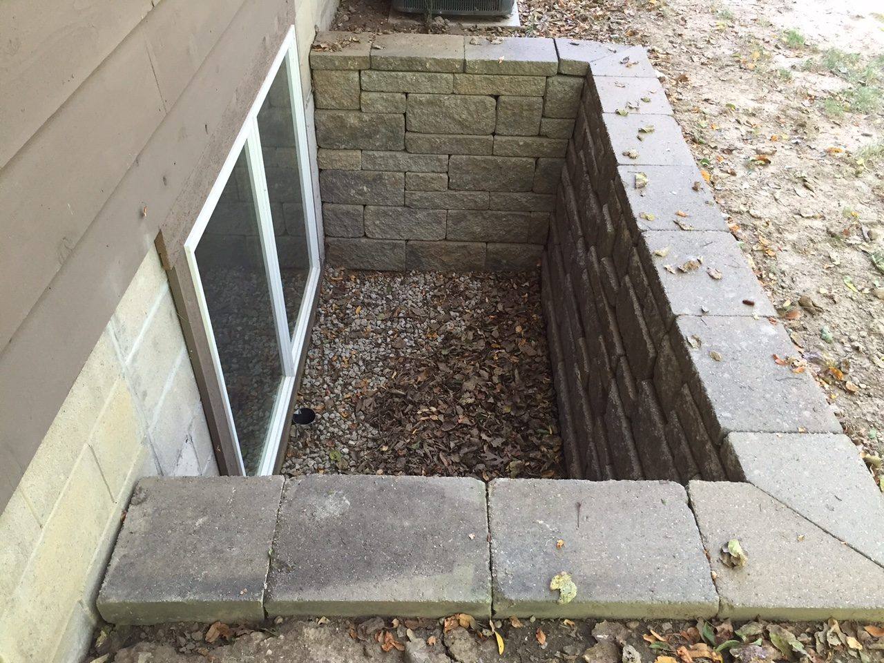 Block retaining wall built around a basement egress window