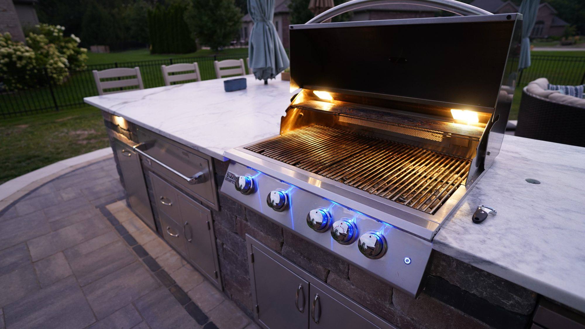 Open built-in grill with control-panel lights in a stone outdoor kitchen