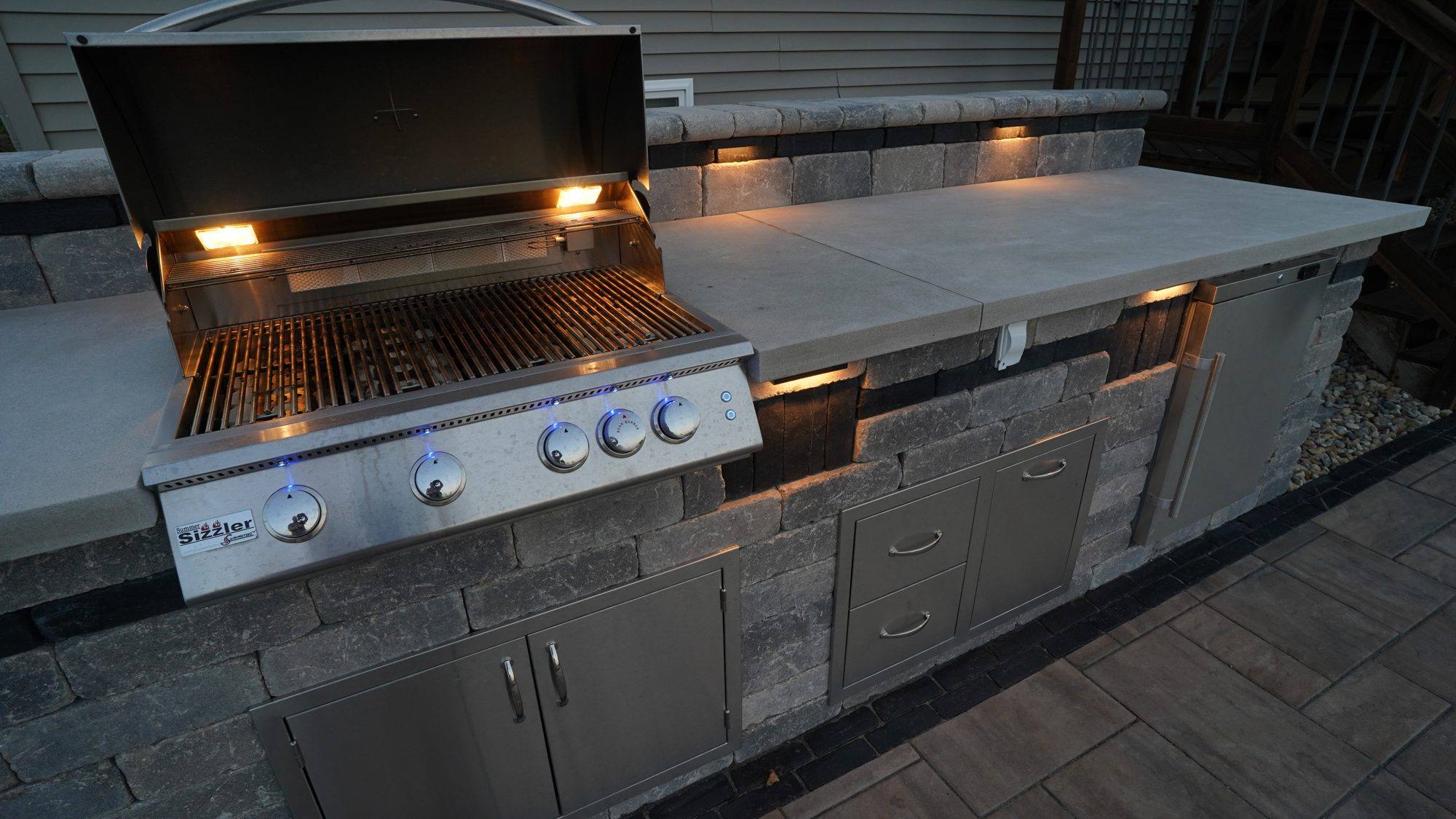 Built-in grill and storage with under-counter lighting in an outdoor kitchen