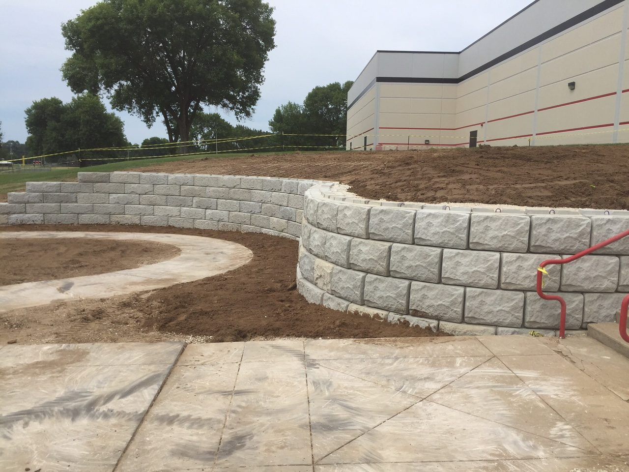 Large curved block retaining wall being installed at a commercial building