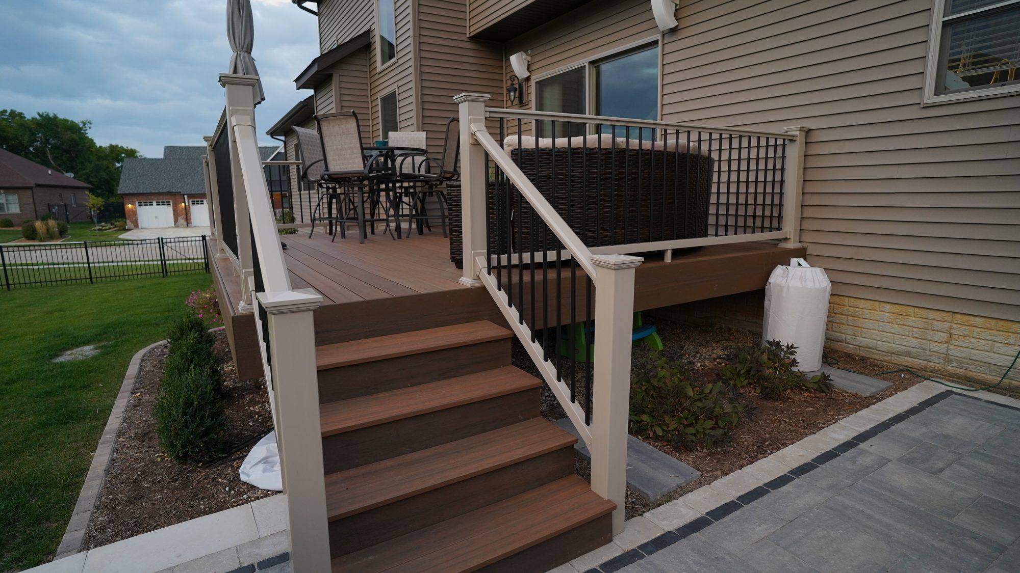 Composite deck stairs leading down to a paver patio and lawn
