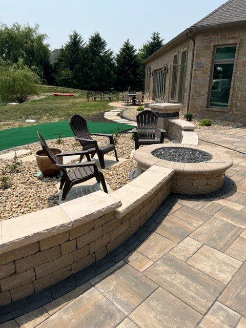 Fire pit built into a curved paver seat wall with Adirondack chairs
