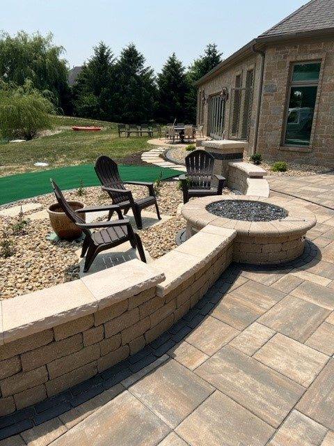Fire pit built into a curved paver seat wall with Adirondack chairs