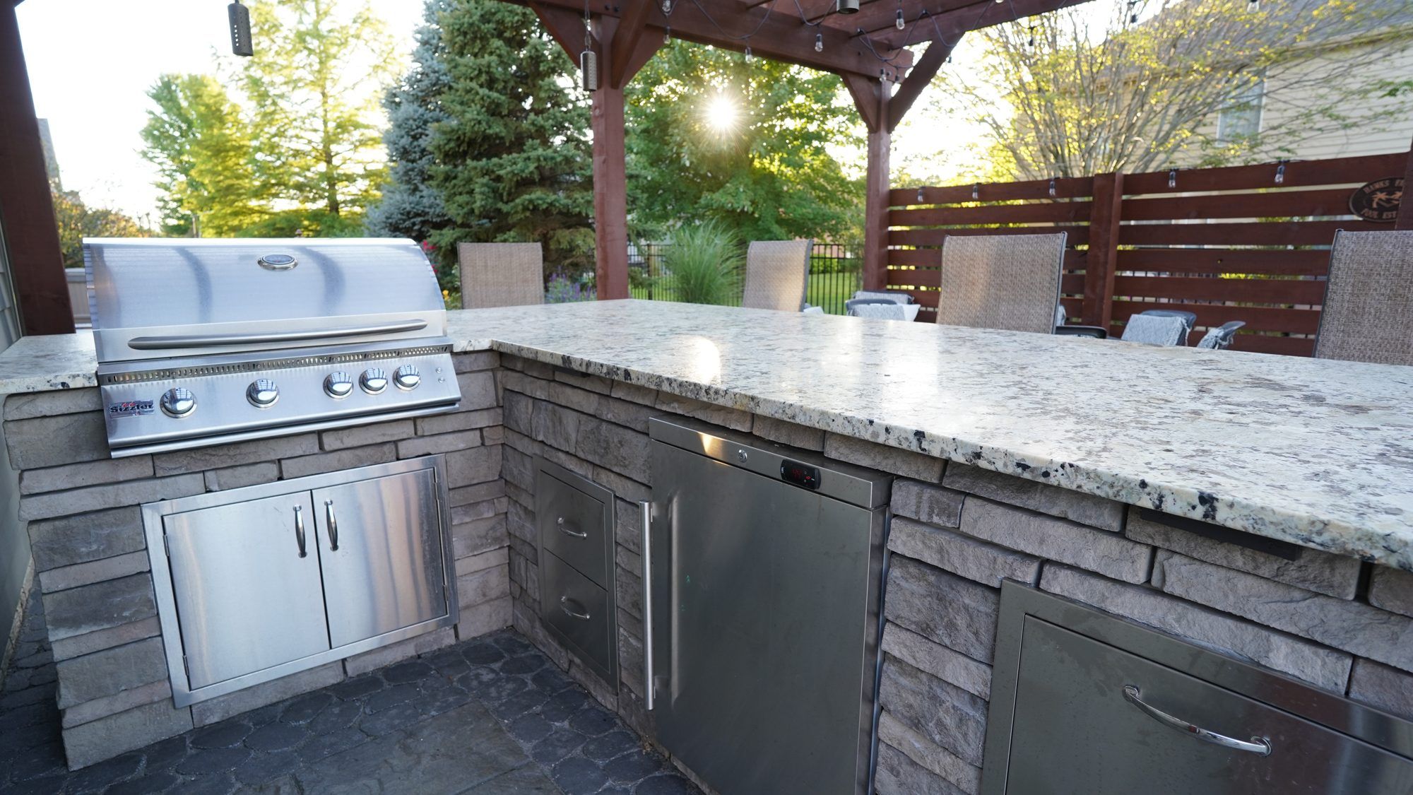 Granite-topped outdoor kitchen with a built-in grill under a pergola