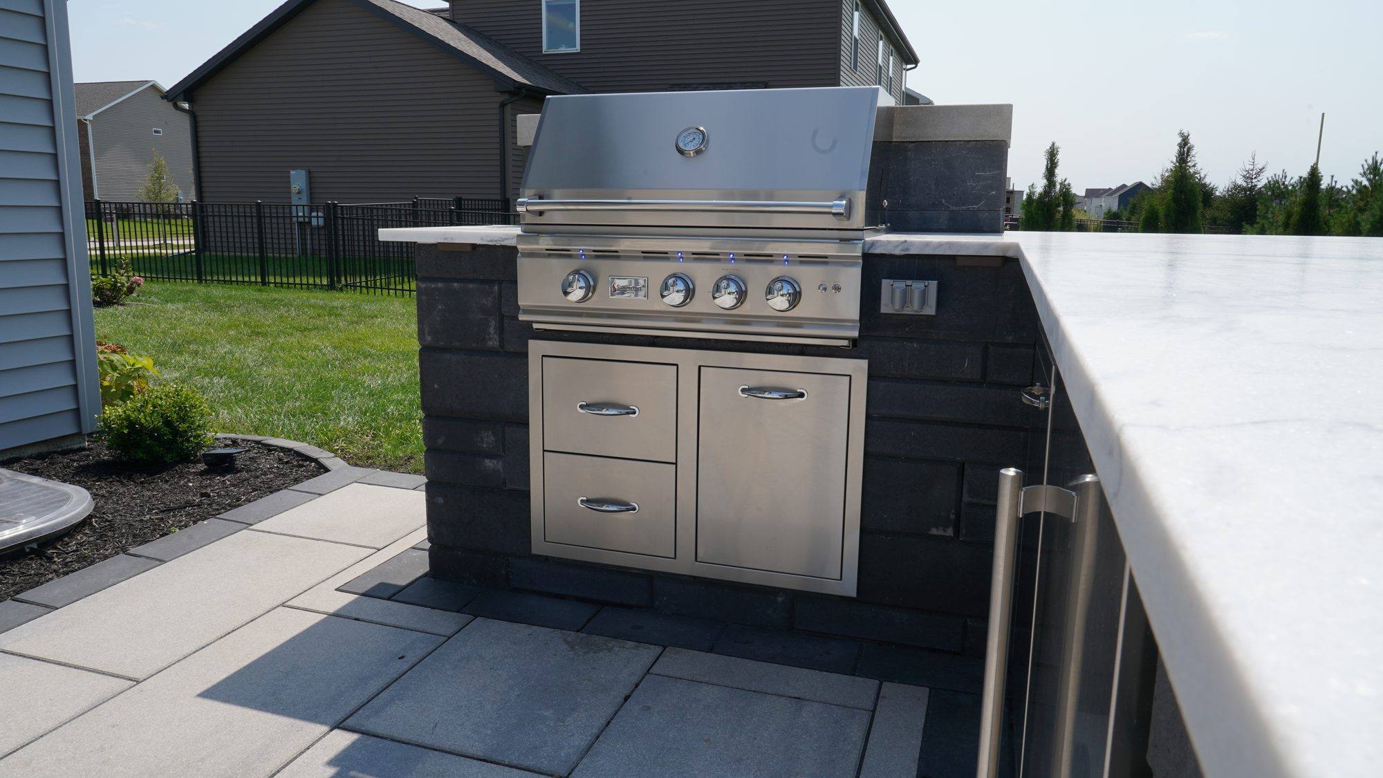 Modern outdoor kitchen island with stainless grill and white counter