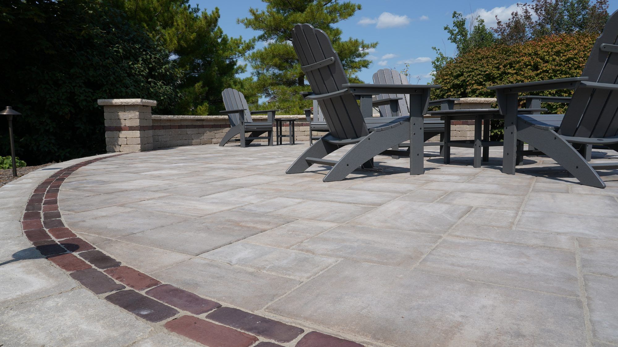 Paver patio with a brick border, Adirondack chairs and a seat wall