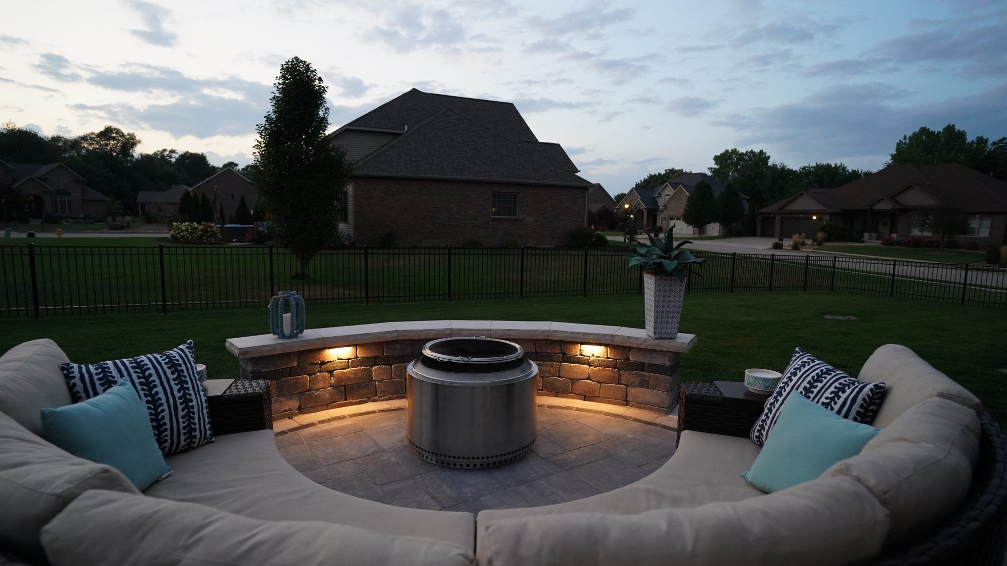 Paver patio with a round fire pit, curved seat wall and outdoor sectional