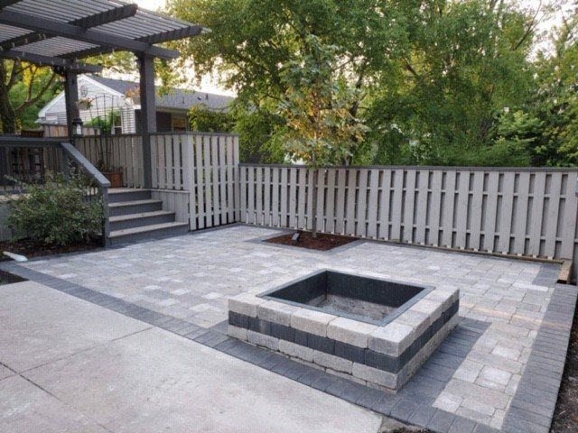 Paver patio with a square sunken fire pit beside a pergola