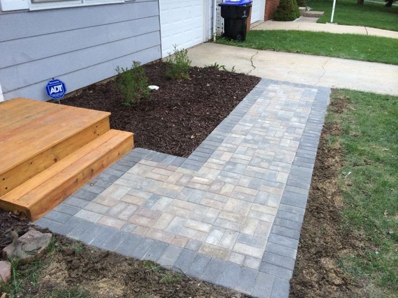 Paver walkway and cedar steps with a fresh mulch bed beside a home