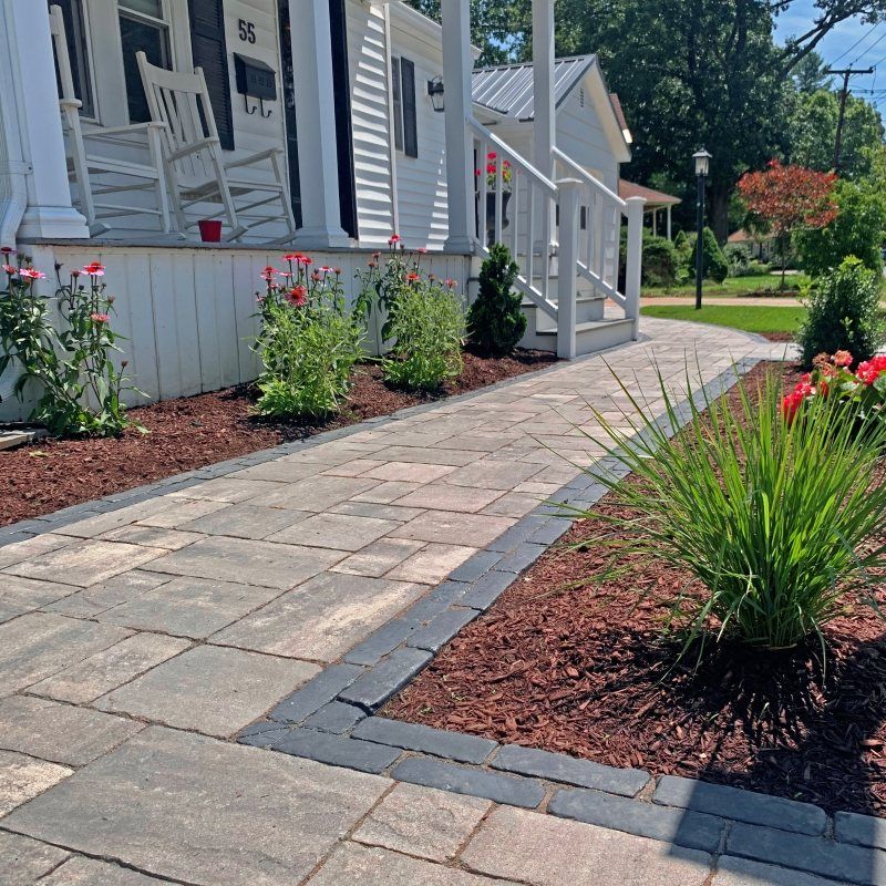 Paver walkway between fresh landscape beds leading to a front door