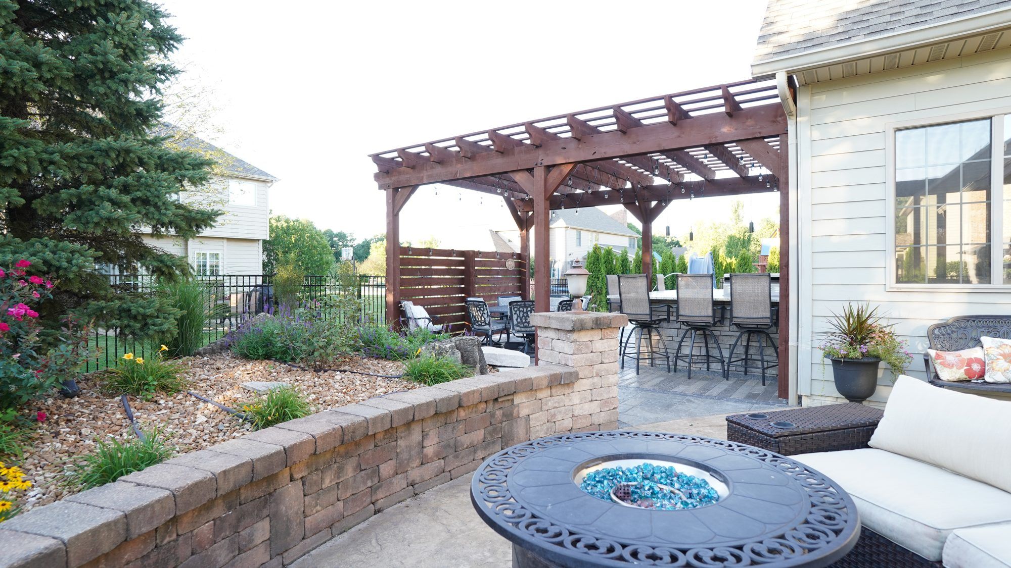 Pergola patio with a fire table, seat wall and landscape beds