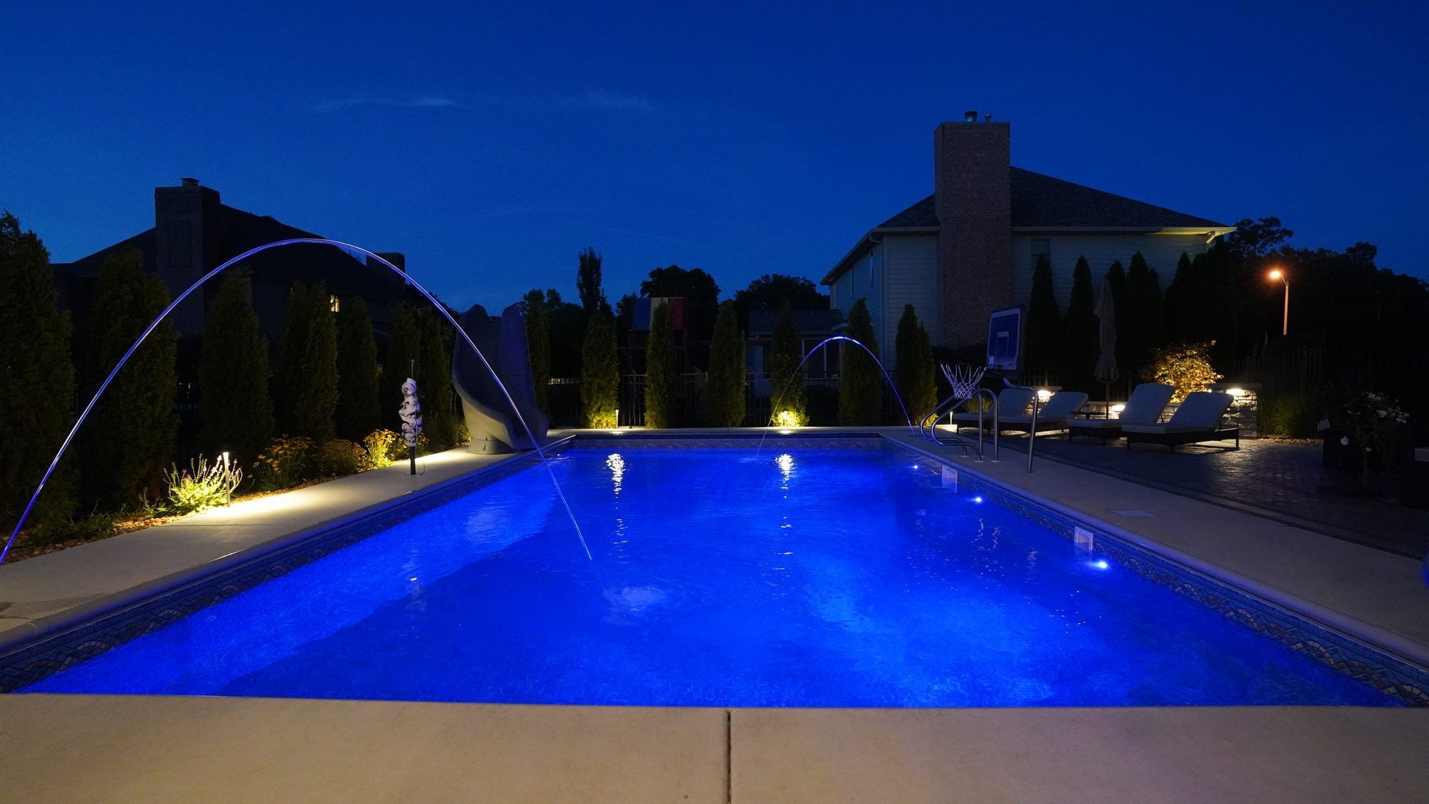 Pool with deck jets and landscape lighting at night