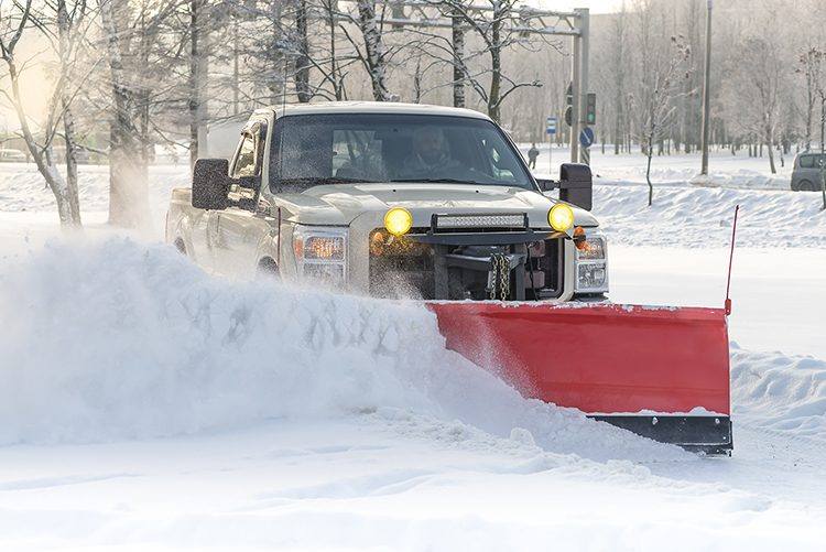 Plow truck pushing a wall of snow in a winter storm